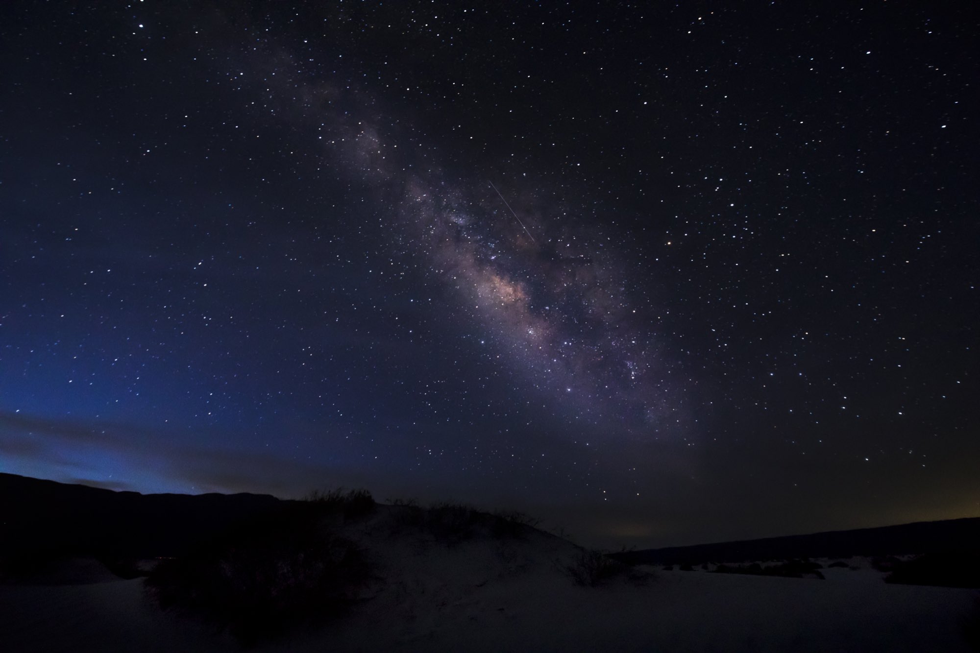 Vía Láctea sobre dunas de arena blanca en un cielo estrellado nocturno